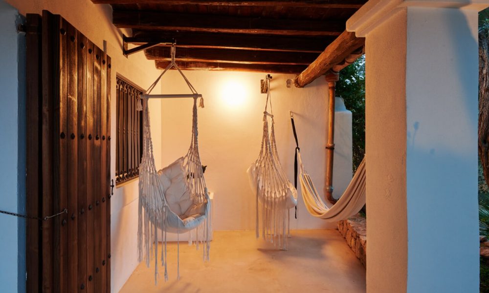 Covered outdoor area with hanging chairs and hammock at dusk