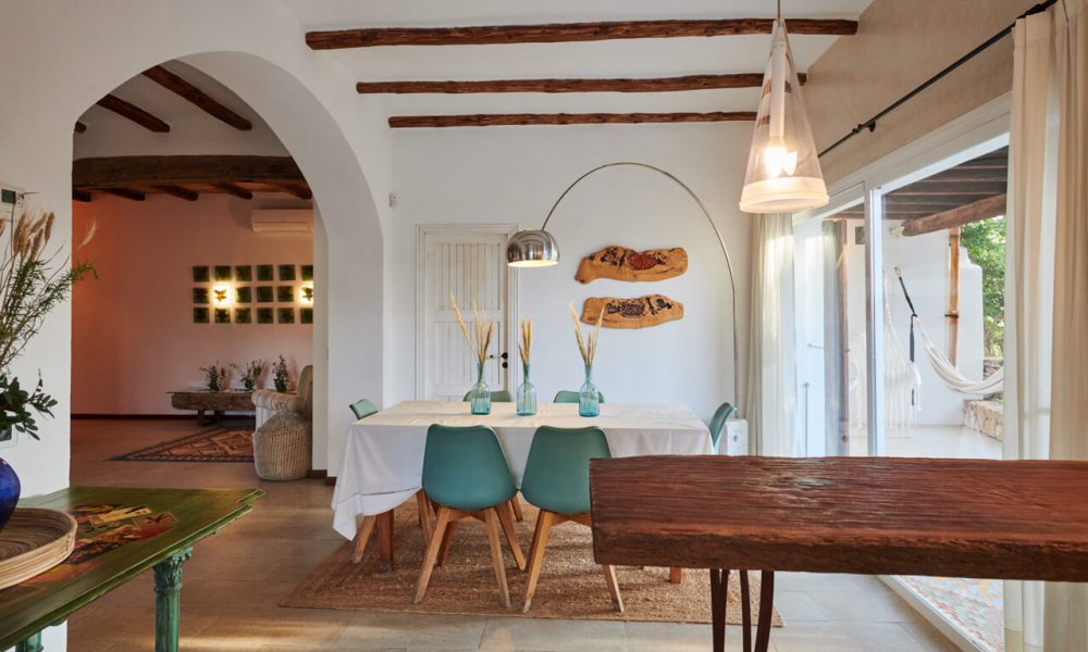 Open-plan dining area with wooden beams, green chairs, and large windows